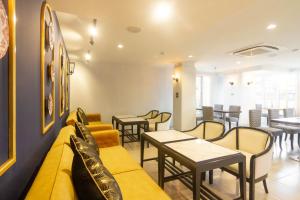 a waiting room with a yellow couch and tables and chairs at Montree Phuket Hotel in Phuket Town