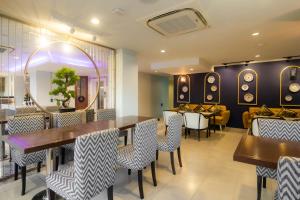 a restaurant with tables and chairs and a mirror at Montree Phuket Hotel in Phuket Town
