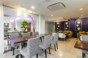 a restaurant with tables and chairs and a mirror at Montree Phuket Hotel in Phuket Town