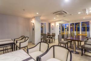 a dining room with tables and chairs and windows at Montree Phuket Hotel in Phuket Town