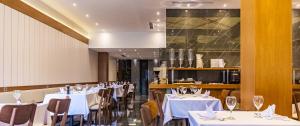 a dining room with white tables and chairs at Hotel Prishtina in Prishtinë