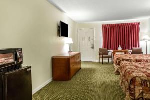 a hotel room with two beds and a television at Rodeway Inn in Groton