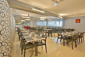 une grande salle à manger avec des tables et des chaises dans l'établissement Downtown Business Hotel, à Singapperumālkovil