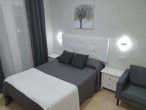 a hotel room with two beds and a chair at Hostal Málaga in Arcos de la Frontera