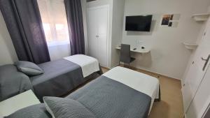 Habitación pequeña con 2 camas y TV. en Hostal Málaga en Arcos de la Frontera