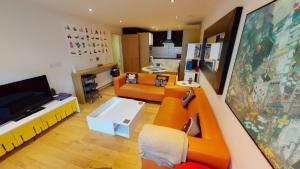 a living room with an orange couch and a tv at Central Perks Apartment (sleeps 4) in Hull