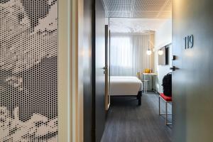 a hotel room with a bed and a door leading to a bedroom at Ibis Montlhery Paris Sud in Montlhéry