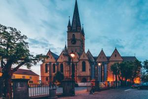 una vieja iglesia con una torre de reloj en una calle en Gasthof Sara en Sibiu