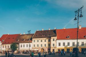 um grupo de edifícios com pessoas andando na frente deles em Gasthof Sara em Sibiu
