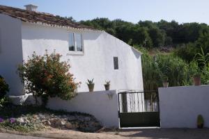 une maison blanche avec une clôture et des fleurs dans l'établissement Casa Da Cabeça, à Faro