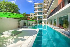 een zwembad met een parasol naast een gebouw bij Wabi Sabi Boutique Hotel - SHA Extra Plus in Kamala Beach