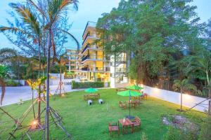 einen Garten mit Tischen und grünen Sonnenschirmen vor einem Gebäude in der Unterkunft Wabi Sabi Boutique Hotel - SHA Extra Plus in Kamala Beach