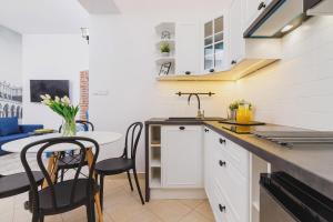a kitchen with white cabinets and a table with chairs at Zamenhofa Studio Kraków by Renters in Krakow