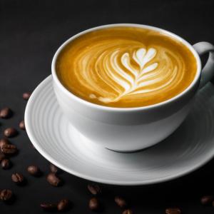 a cup of coffee on a plate with coffee beans at Montree Phuket Hotel in Phuket Town