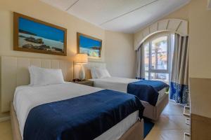 a hotel room with two beds and a window at Playa Linda Beach Resort in Palm-Eagle Beach