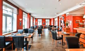 a restaurant with tables and chairs and red walls at Hotel Stadt Kappeln in Kappeln