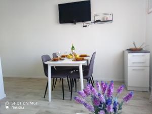 a dining room table with chairs and a tv on the wall at Apartmani Darko in Međugorje