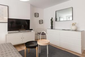 - un salon blanc avec une télévision et une chaise dans l'établissement Appartements de la Pléiade, à Strasbourg