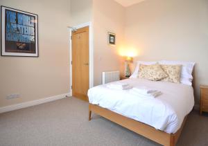 a bedroom with a large bed with white sheets at Towennan - four bedroomed apartment in quiet seaside village. in Gwithian