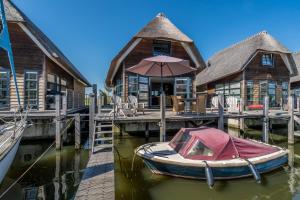 a small boat is docked in front of a house at Nautic Rentals - Watervilla's Zuiderhoeve in De Heen