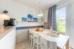 a kitchen with a white table and chairs and a window at Village Pierre & Vacances Belle Dune in Fort-Mahon-Plage