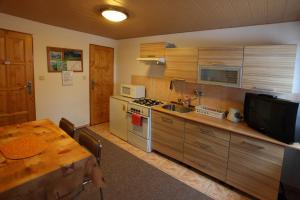 a kitchen with wooden cabinets and a table and a television at Penzión Antónia in Habovka