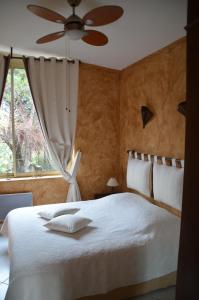 a bedroom with a white bed with a ceiling fan at Les Mayombes in Roquebrune-sur-Argens +131 photos