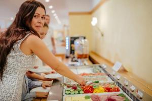 a woman standing in front of a buffet with food at Hotel Akademie in Chocerady
