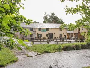 a building with picnic tables in front of a river at Black Lion Barn Retreat in Shrewsbury