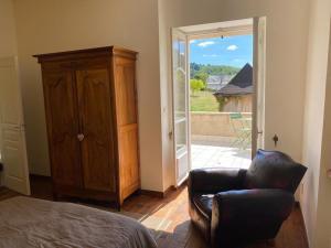 a living room with a leather chair and a sliding glass door at Le Clos St Georges in Entraygues-sur-Truyère