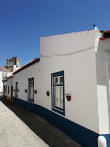 - un bâtiment blanc avec des fenêtres noires dans une rue dans l'établissement Maria`s Guesthouse, à Beja