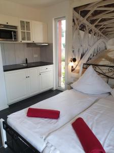 uma cozinha com 2 camas brancas e almofadas vermelhas em Apartmenthaus in Walle em Walle