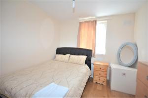 een slaapkamer met een bed met een spiegel en een dressoir bij London Deluxe 6 Bedroom House in Dagenham