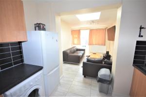 a kitchen with a white refrigerator and a living room at London Deluxe 6 Bedroom House in Dagenham