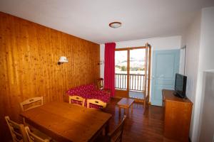 una sala da pranzo con tavolo in legno e TV di Residence Le Hameau du Puy by Actisource a Le Dévoluy