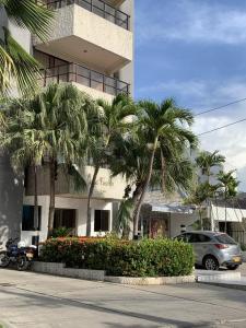 une voiture garée devant un immeuble avec des palmiers dans l'établissement Apartahotel Isla Fuerte Piso 4, à Carthagène des Indes