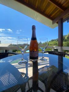 a bottle of wine sitting on a table with two glasses at Casa no Vale dos Vinhedos em Bento Gonçalves in Bento Gonçalves