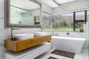 Un baño con dos lavabos, una bañera y un espejo. en Villa de luxe, en Franschhoek 31 fotos más