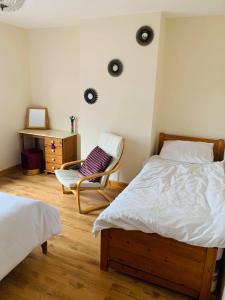 a bedroom with two beds and a chair and a desk at Private Apartment in Dumfries