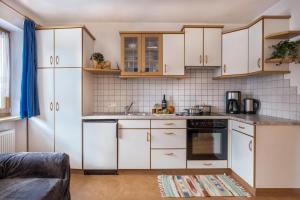 a kitchen with white cabinets and a stove top oven at Haus Belodei - Apt B in San Martino in Badia