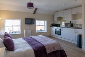a bedroom with a large bed and a kitchen at Isabella House - Hereford City Centre Aparthotel, By RentMyHouse in Hereford