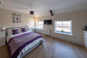 a bedroom with a large bed and two windows at Isabella House - Hereford City Centre Aparthotel, By RentMyHouse in Hereford