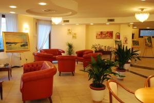 ein Wartezimmer mit roten Stühlen, Tischen und Pflanzen in der Unterkunft Europa Stabia Hotel in Castellammare di Stabia