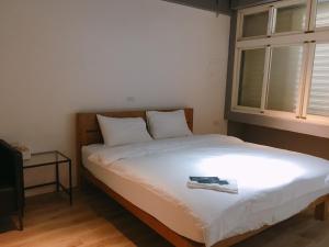 a bedroom with a white bed with a window at Bao Dao Da Lou in Suao