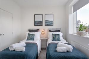 two twin beds in a room with two windows at Luxury Serviced Apartments Stevenage, Hertfordshire in Stevenage