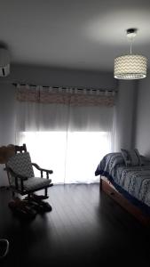 ein Schlafzimmer mit einem Bett, einem Stuhl und einem Fenster in der Unterkunft DUPLEX VISTAS DE HAEDO in El Palomar