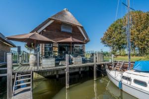 ein Haus auf einem Dock neben einem Boot in der Unterkunft Nautic Rentals - Watervilla's Zuiderhoeve in De Heen