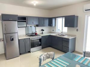 uma cozinha com electrodomésticos cinzentos e uma mesa em Casa nueva recien equipada y completa. em Chihuahua