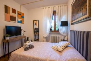 - une chambre avec un lit et une télévision dans l'établissement La Stagione dell'Arte B&B, à Stiava