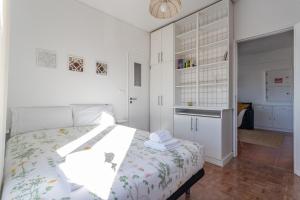 a white bedroom with a bed and a kitchen at Beach House Cascais in Estoril